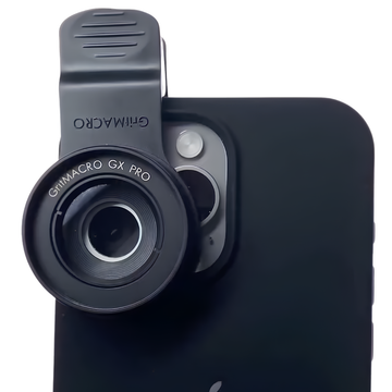 Vista frontale della lente macro GritMACRO GX PRO, agganciata con una clip nera a uno smartphone in una custodia nera, pronta per la fotografia macro professionale.